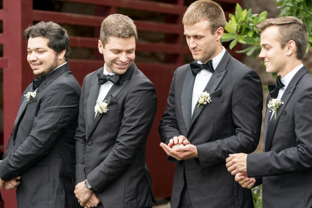 One of the groomsmen gently holds the couple’s wedding rings in her open palms during the ring blessing. The rings are small, glinting gold bands passed with reverence from person to person. Blurred figures of the wedding party surround her. This Lancaster wedding photo captures a meaningful spiritual tradition in motion.