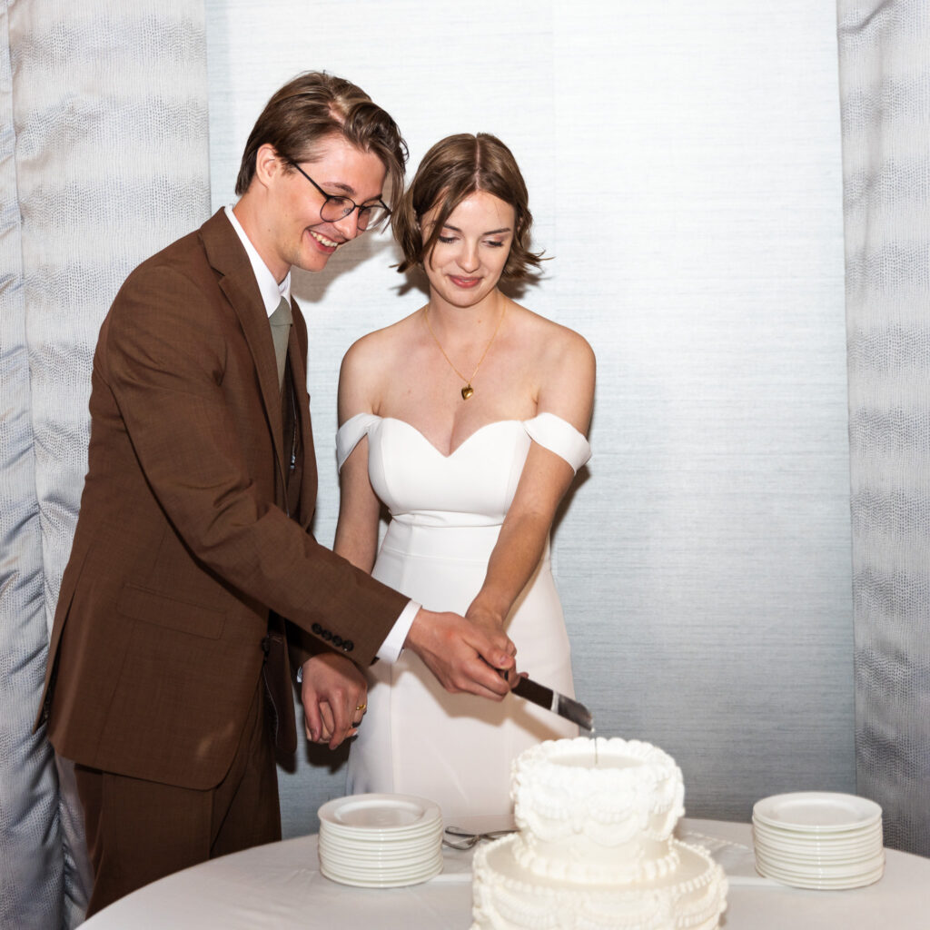 Couple cutting their white wedding cake together and smiling during their Read House Wedding reception in the Chestnut Room.