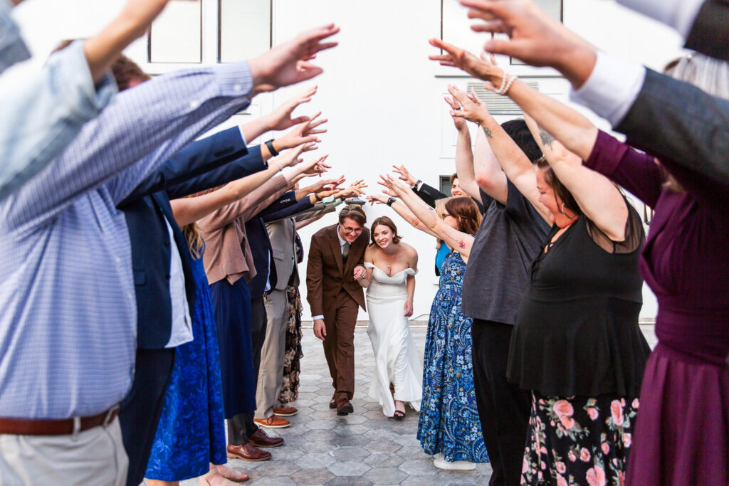 Guests forming a tunnel of raised arms as the bride and groom joyfully make their exit from the Read House Wedding celebration.