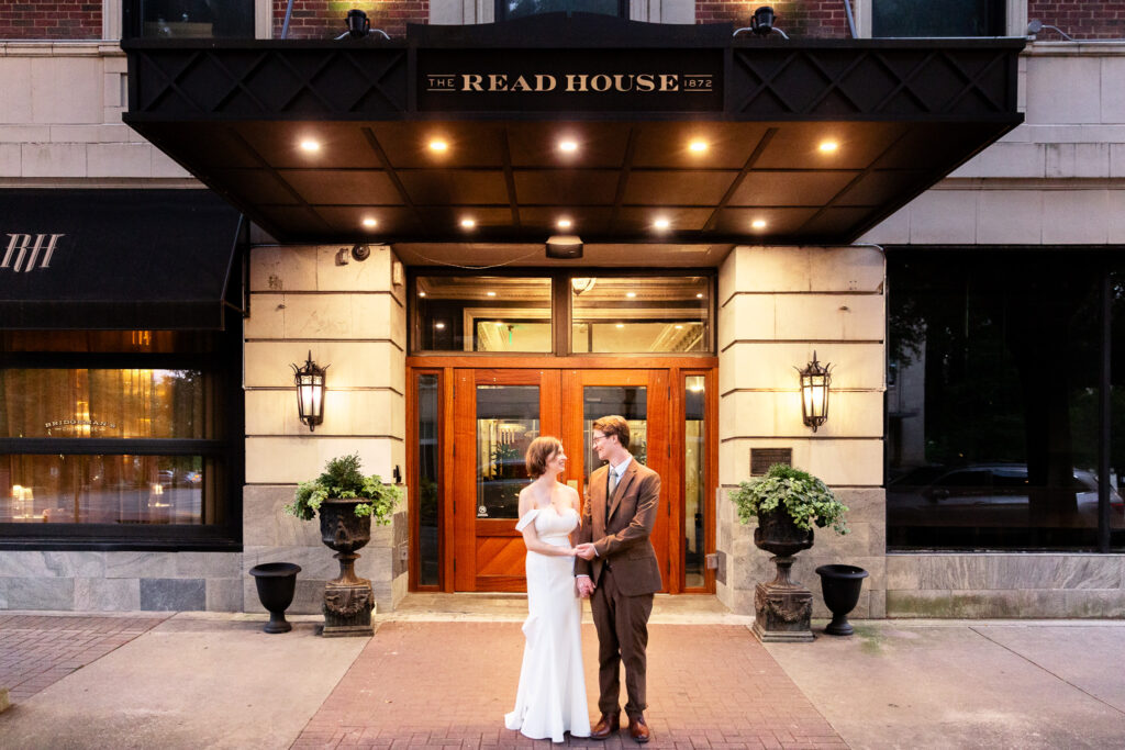 Evening portrait of the couple standing outside the front entrance of The Read House under its black awning and golden lights, marking the close of their Read House Wedding day.