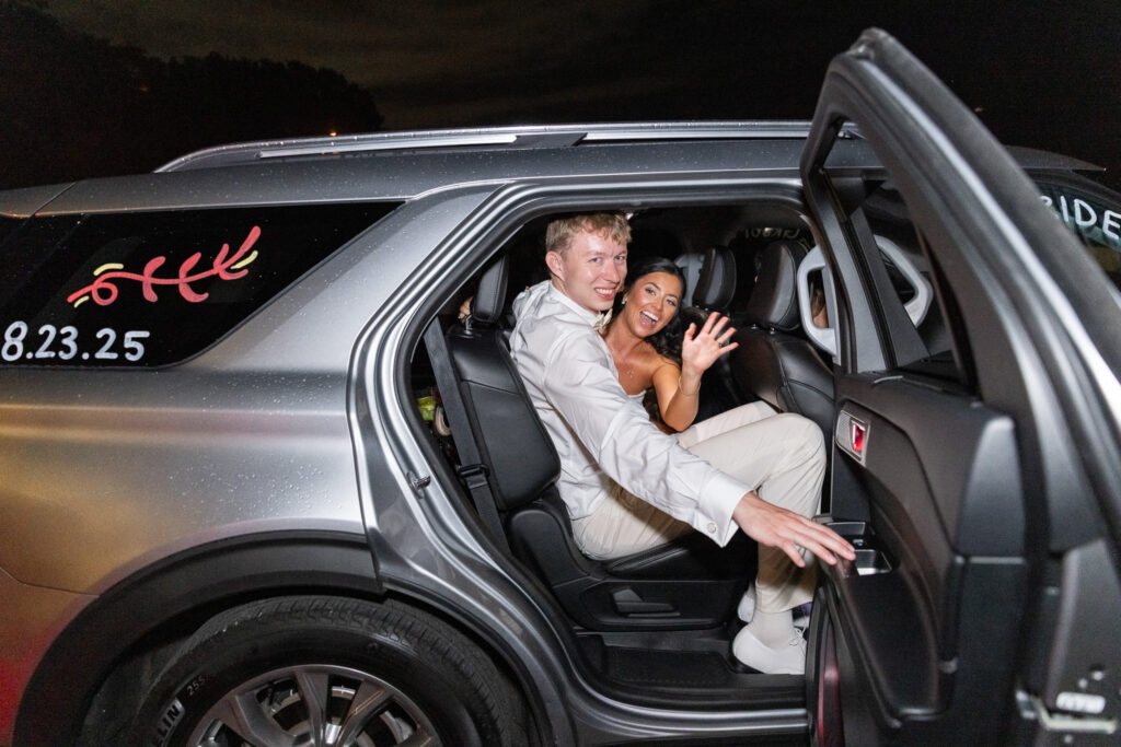 The bride and groom smile and wave from inside their car, newly decorated with their wedding date and playful messages. Their joyful exit reflects the celebratory energy outdoor wedding venues in Chattanooga provide for the perfect send-off.