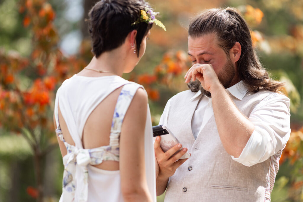 The groom wipes away a tear while holding his vows during an intimate outdoor moment of their Georgia State Park wedding ceremony.