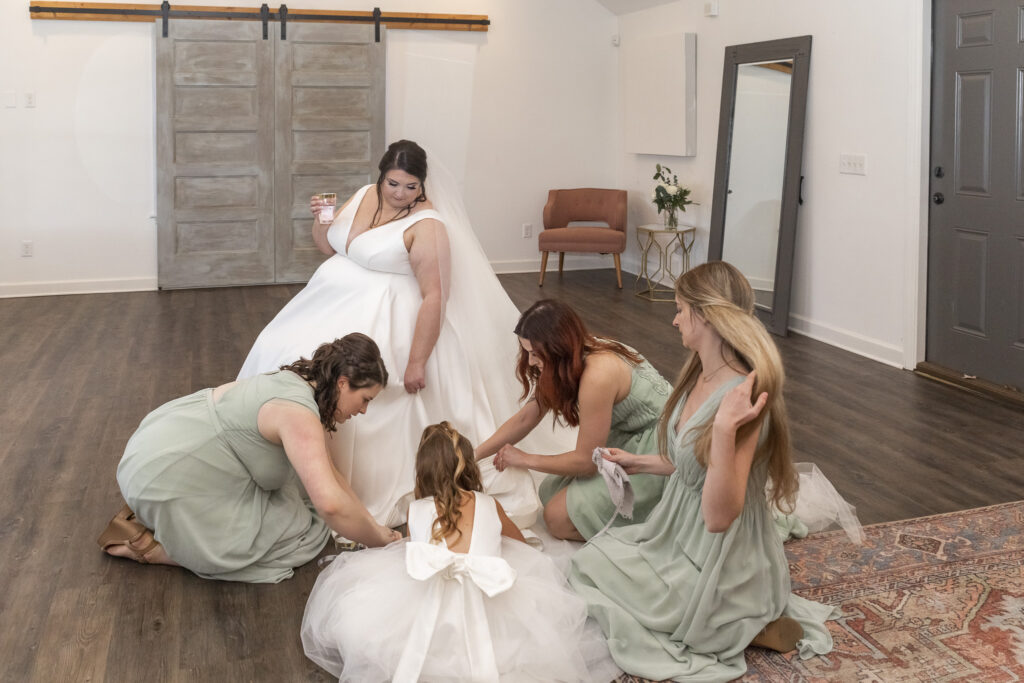 Bridesmaids help spot clean the brides dress, thanks to good wedding dress planning during the final preparations before the ceremony.