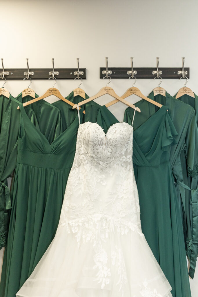 Bridal gown and bridesmaid dresses hanging together on personalized hangers, part of organized wedding dress planning before the big day.