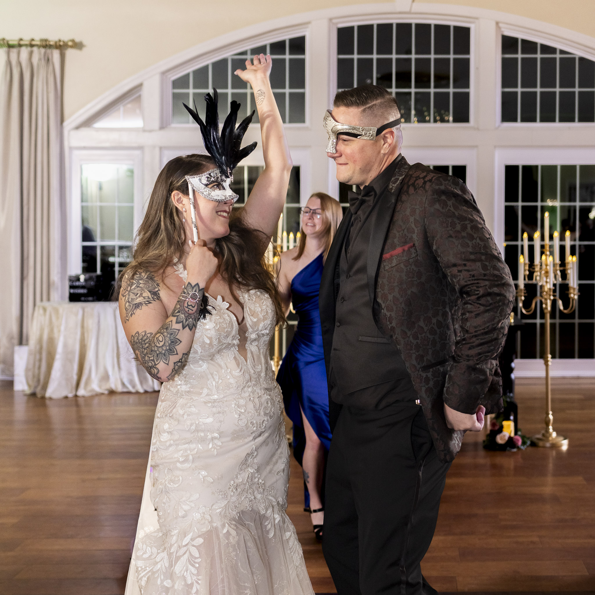 The couple dances together, still wearing their ornate masks, as the bride raises her arm in excitement. Their laughter and connection perfectly embody the fun and theatrical spirit of a masquerade wedding.