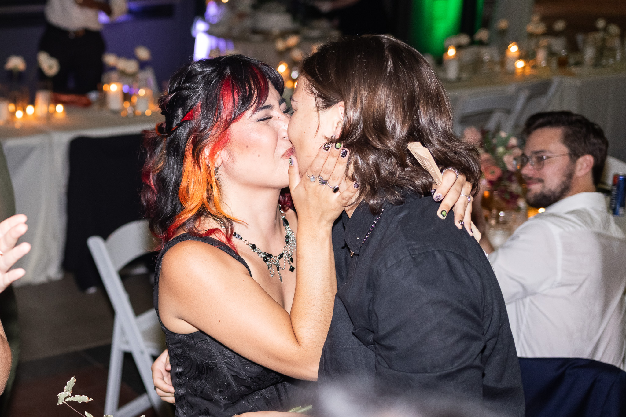 Two wedding guests share a kiss on the dance floor while other guests celebrate around them during a lively reception. Inclusive wedding vendors help create spaces where every guest feels welcomed and celebrated