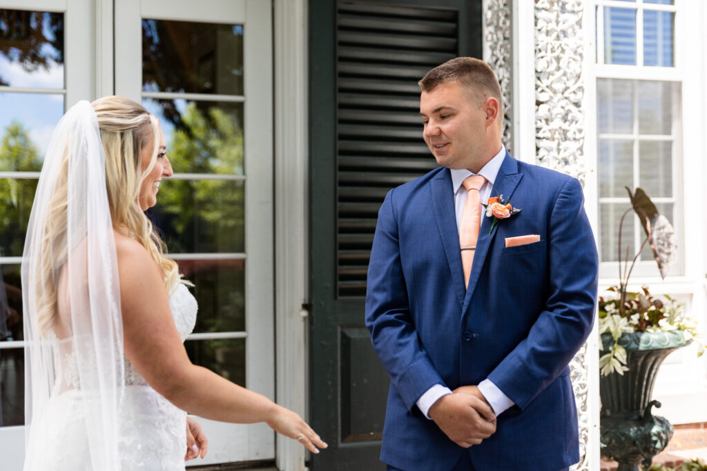 The groom smiles nervously as he turns to see his bride for the first time during their emotional first look outside the estate.