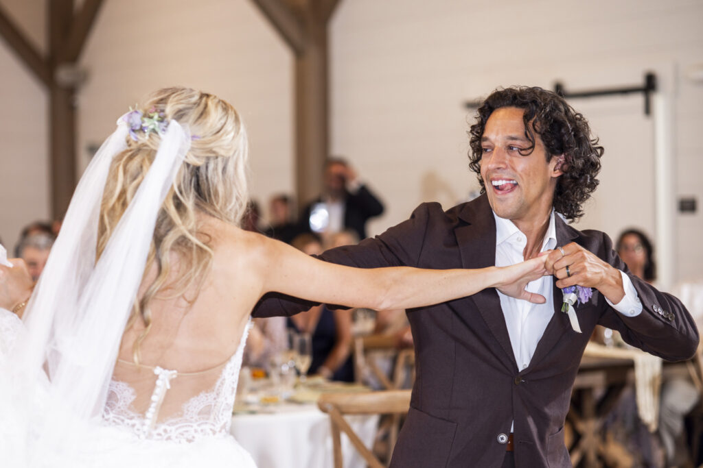 Newlyweds dance together inside a bright reception space as the groom playfully holds the bride’s hand during their South Jersey wedding celebration.